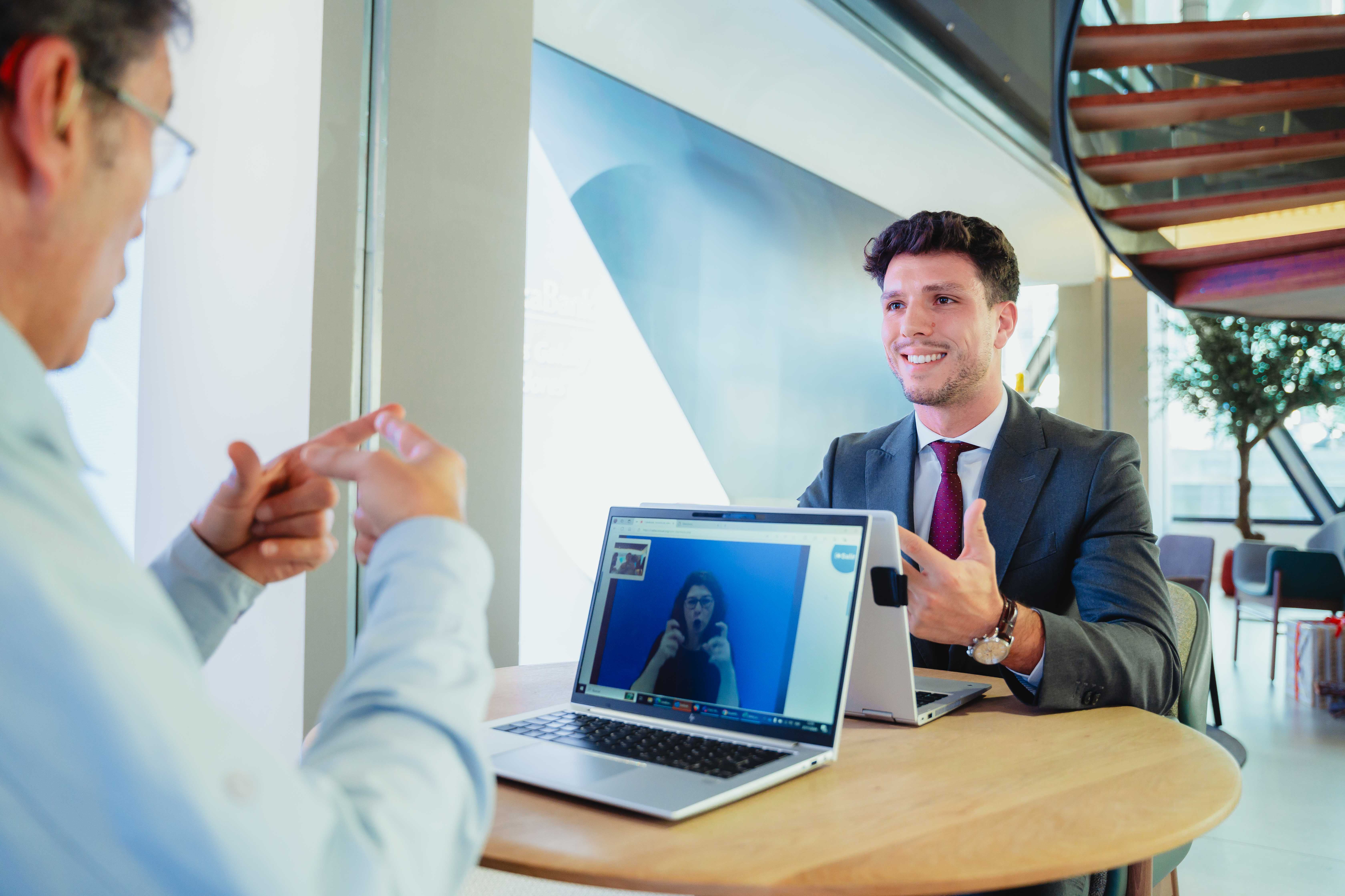 A CaixaBank customer and a manager using the SVisual sign language video interpretation service in an office.